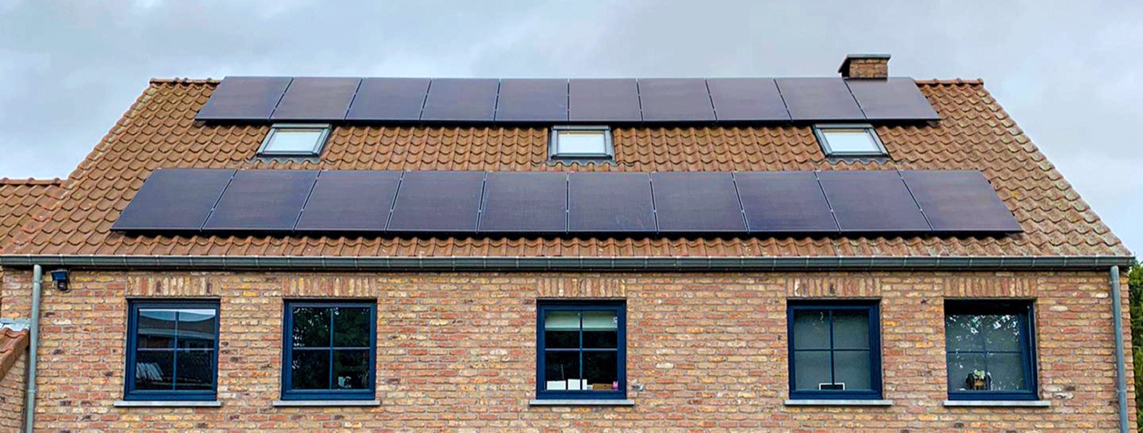 Maison en briques avec deux rangées de panneaux solaires sur un toit en tuiles